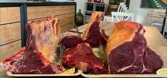 Grandi tagli di carne pronti per la brace, su vassoi sul tavolo della sala di Bombetta